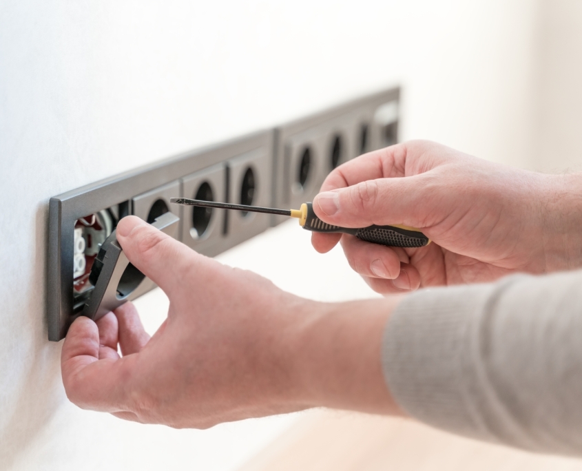 Close, careful hands installing a modern electrical outlet with a small screwdriver