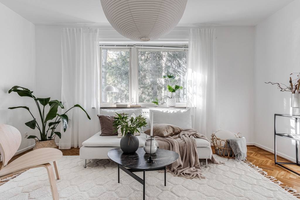 Bright, calm Scandinavian living room with soft natural light, a pendant lamp, and clean white walls